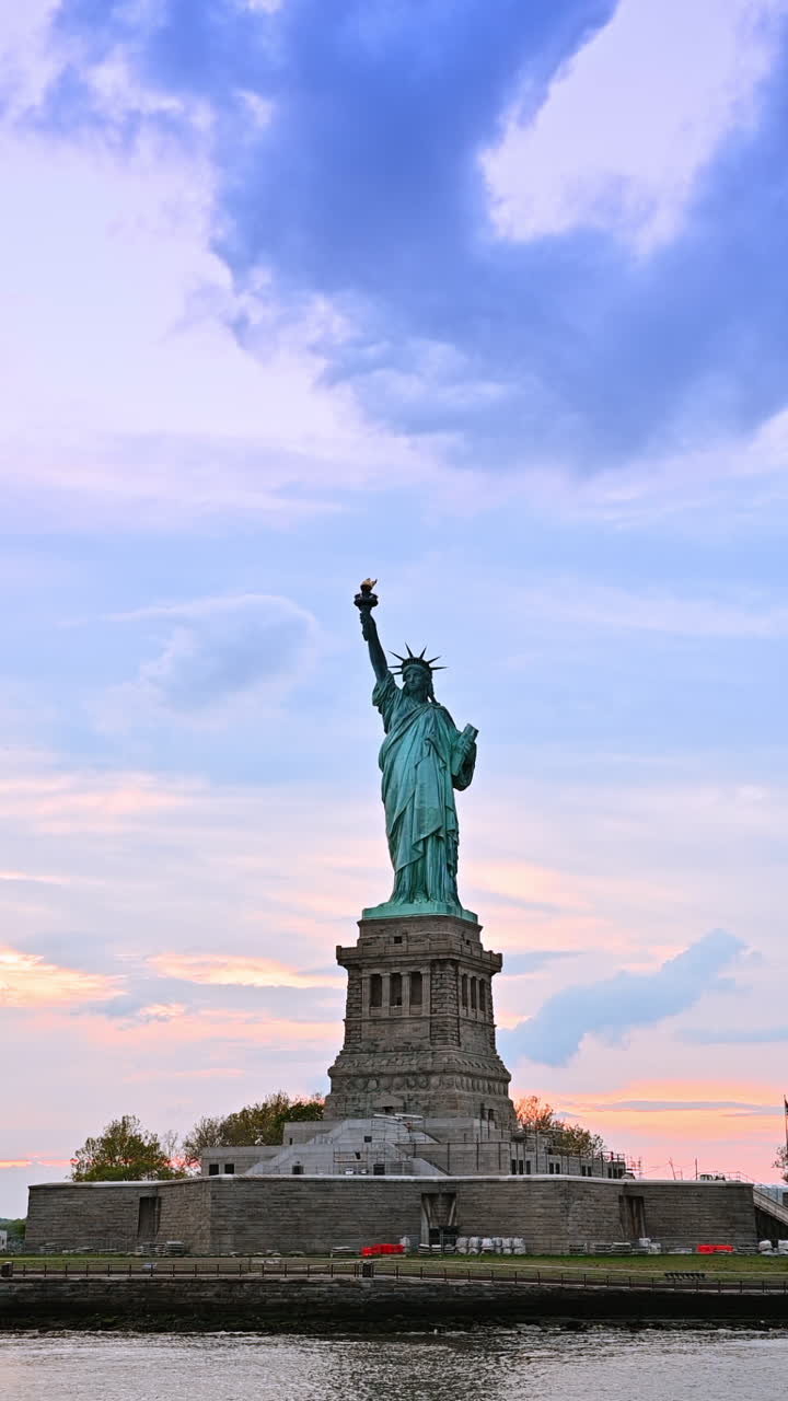 New York, USA, 8 luglio 2025: Visita alla Statua della Libertà, NYC. I turisti ammirano la Statua della Libertà mentre il sole tramonta sul porto di New York, dipingendo il cielo con colori caldi.