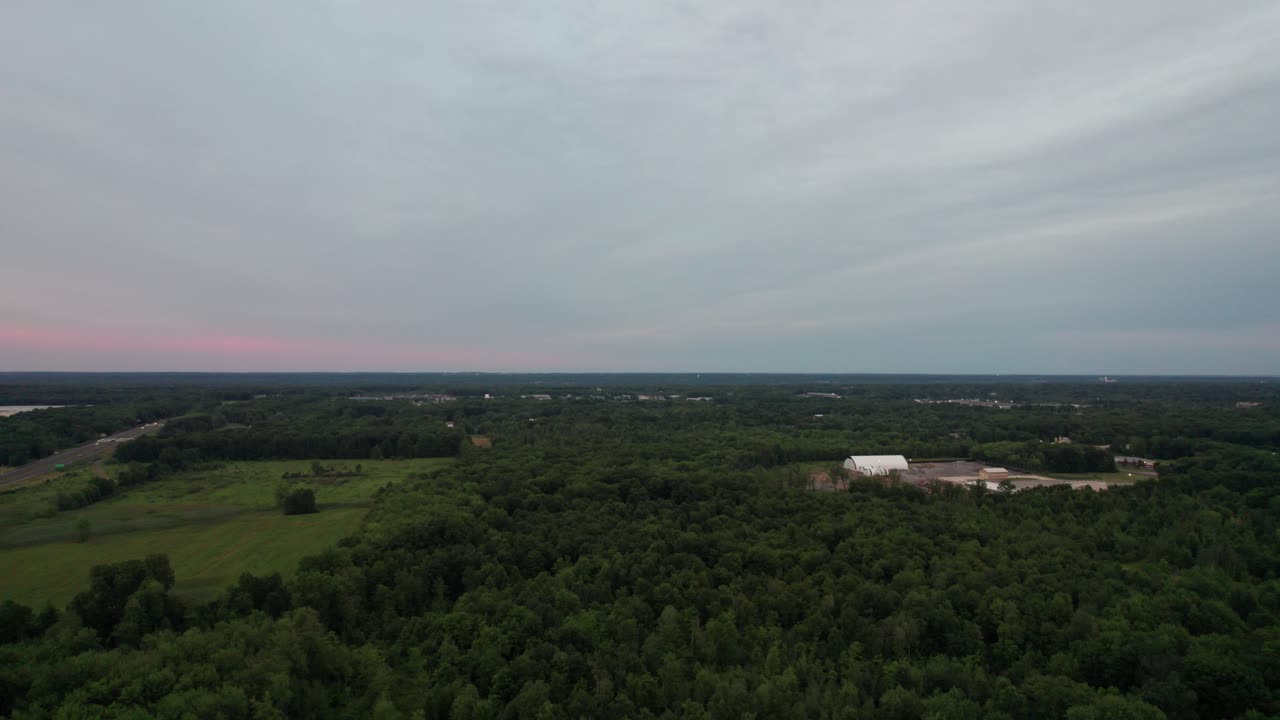 Gün batımında bir orman açıklığının panoramik görünümü.