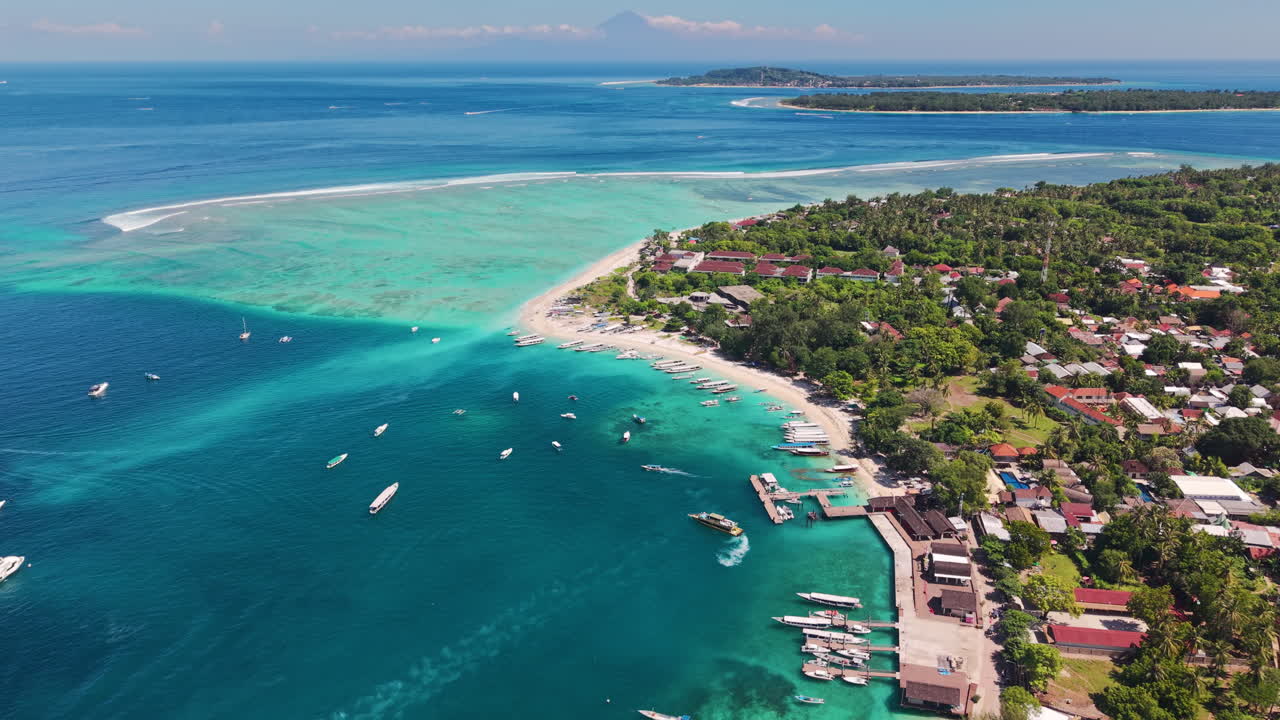 Video aereo con drone della costa di Gili Air con barche, acqua turchese e barriera corallina.