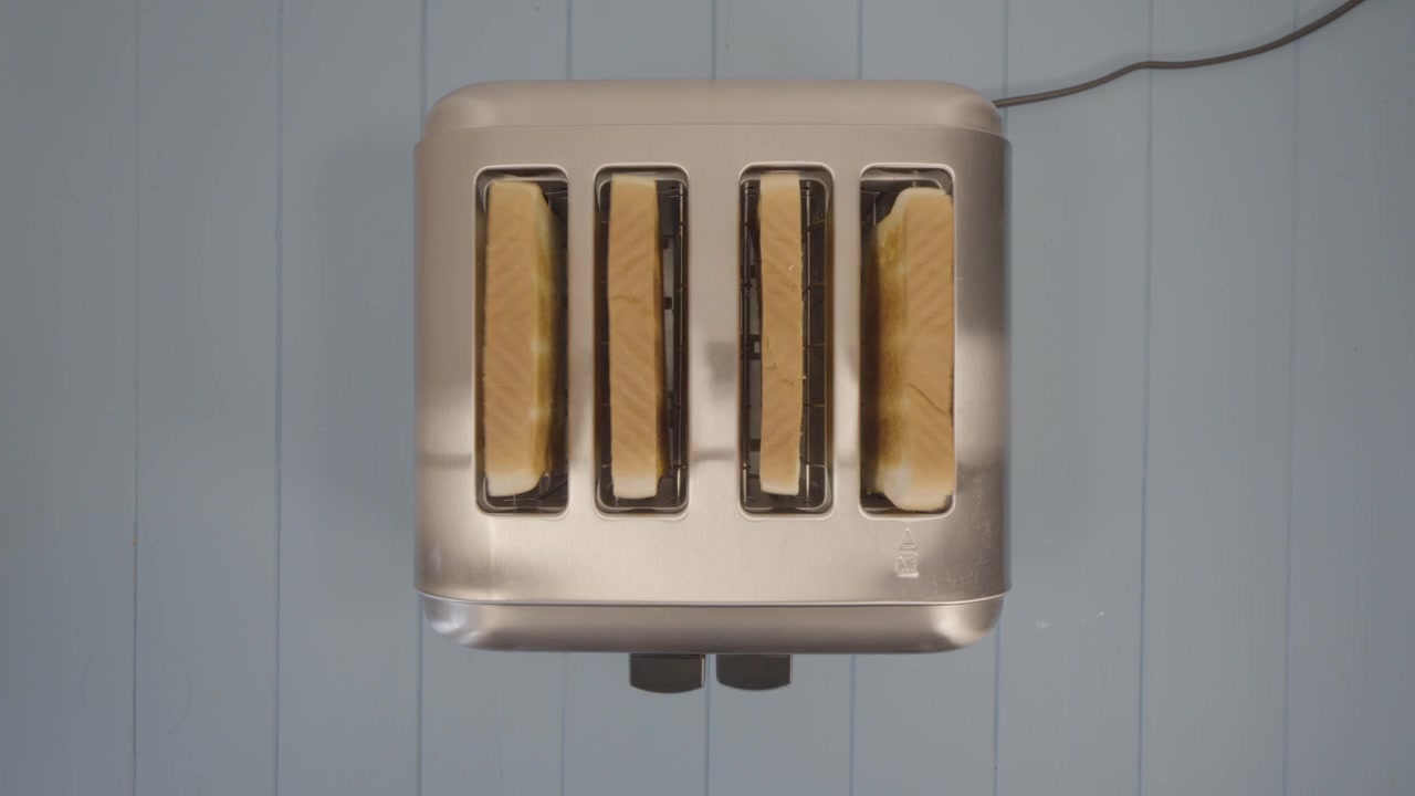 Fugleperspektiv af fire ristede skiver sandwichbrød, der springer op af en forkromet brødrister