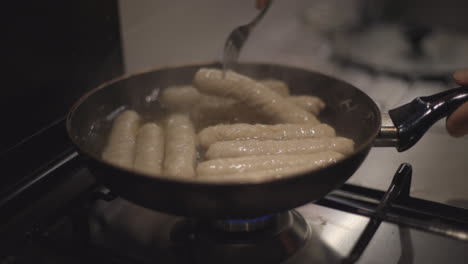 slow motion: man or woman prepare sausages in a pan