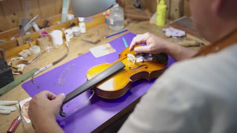 craftsman assembling bow on violin