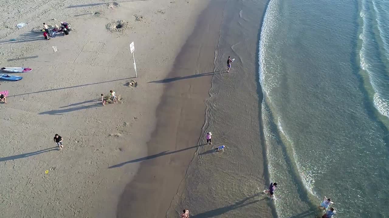 A beach scene with many people and surfboards.