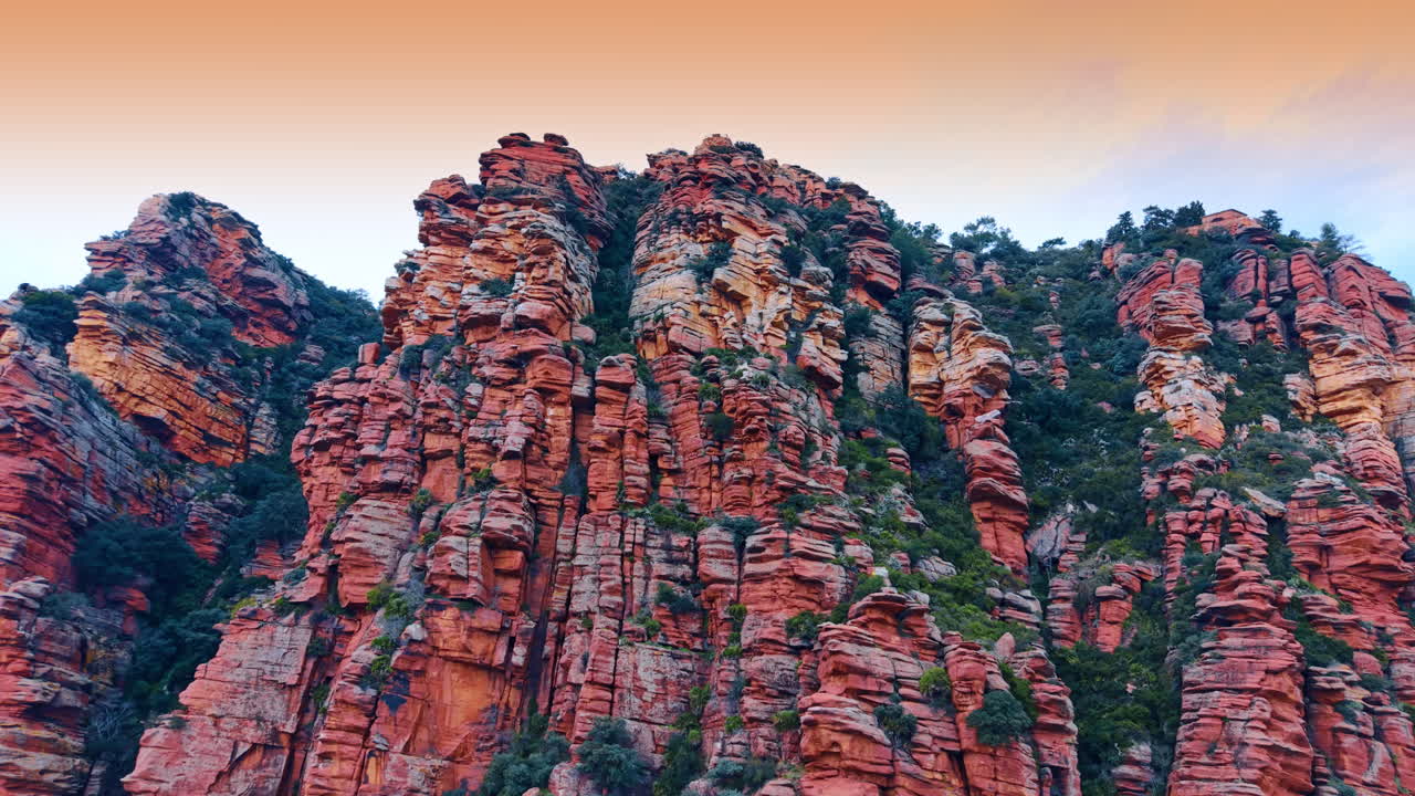 Torri frastagliate di arenaria rossa sotto un vibrante cielo al tramonto. Colonne di arenaria rossa contro un cielo sfumato arancione e rosa durante l'ora d'oro serale.