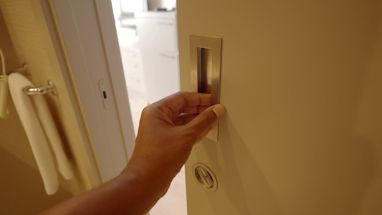 A hand opening a bathroom door