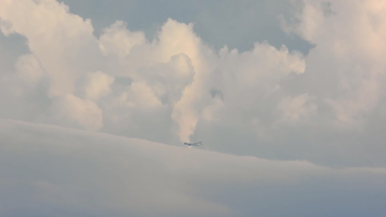 Airplane flies across clouds, sunny day, just after take off.