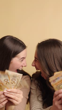 two women celebrating with euro banknotes in joyful mood