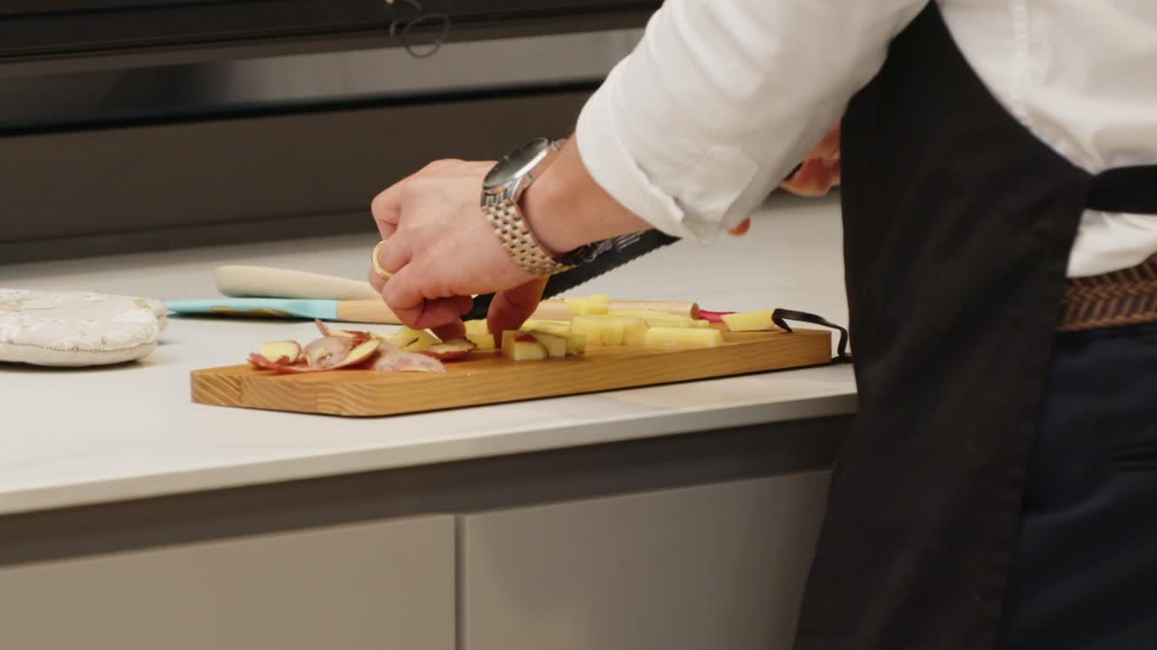 Hands chopping apples on a wooden cutting board in a kitchen
