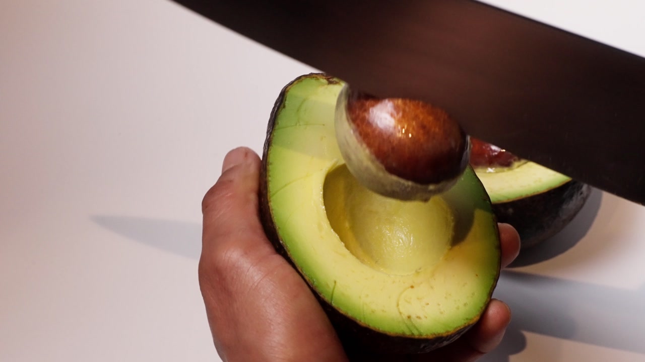 slow motion shot of a man removing the seed of an avocado