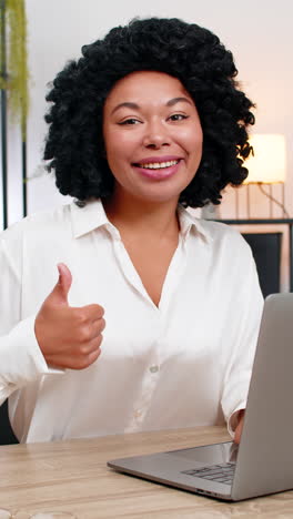 african american businesswoman gives thumbs up at laptop smiling approving successful result today