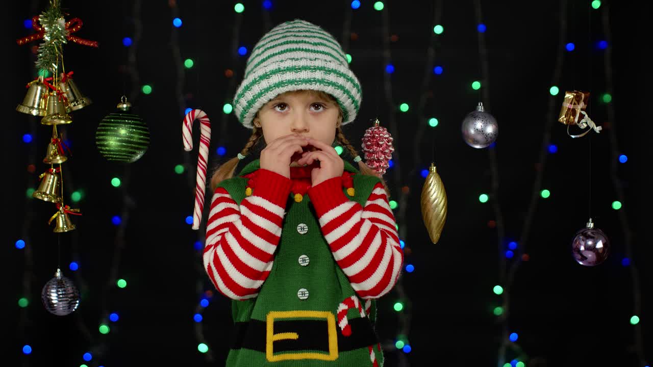 Shy shamed child girl in Christmas elf Santa helper costume posing looking camera making funny faces