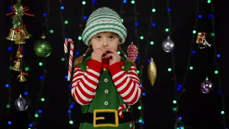 Shy-shamed-child-girl-in-Christmas-elf-Santa-helper-costume-posing-looking-camera-making-funny-faces