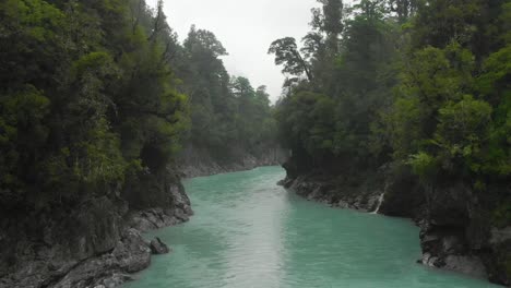 slowmo - aerial drone flight over blue glacier river at hokitika gorge, new zealand