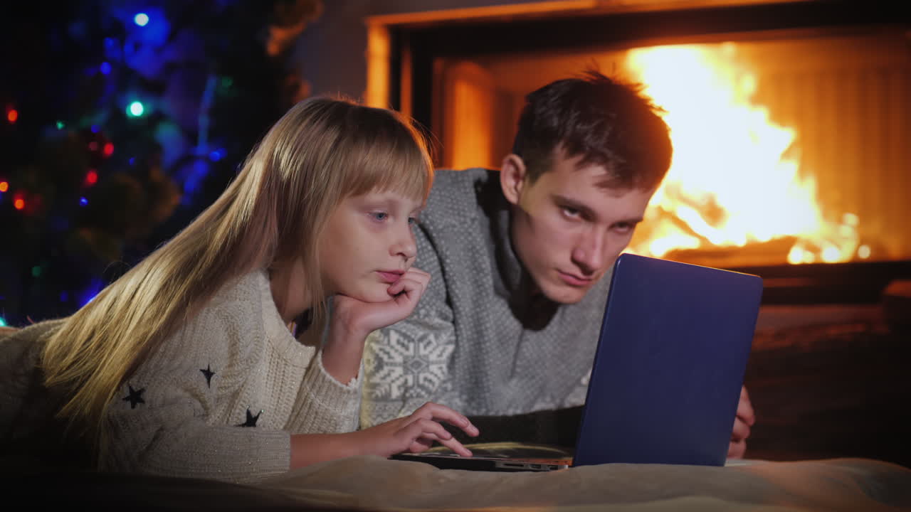 hermano y hermana usan una computadora portátil en la sala de estar junto a la chimenea