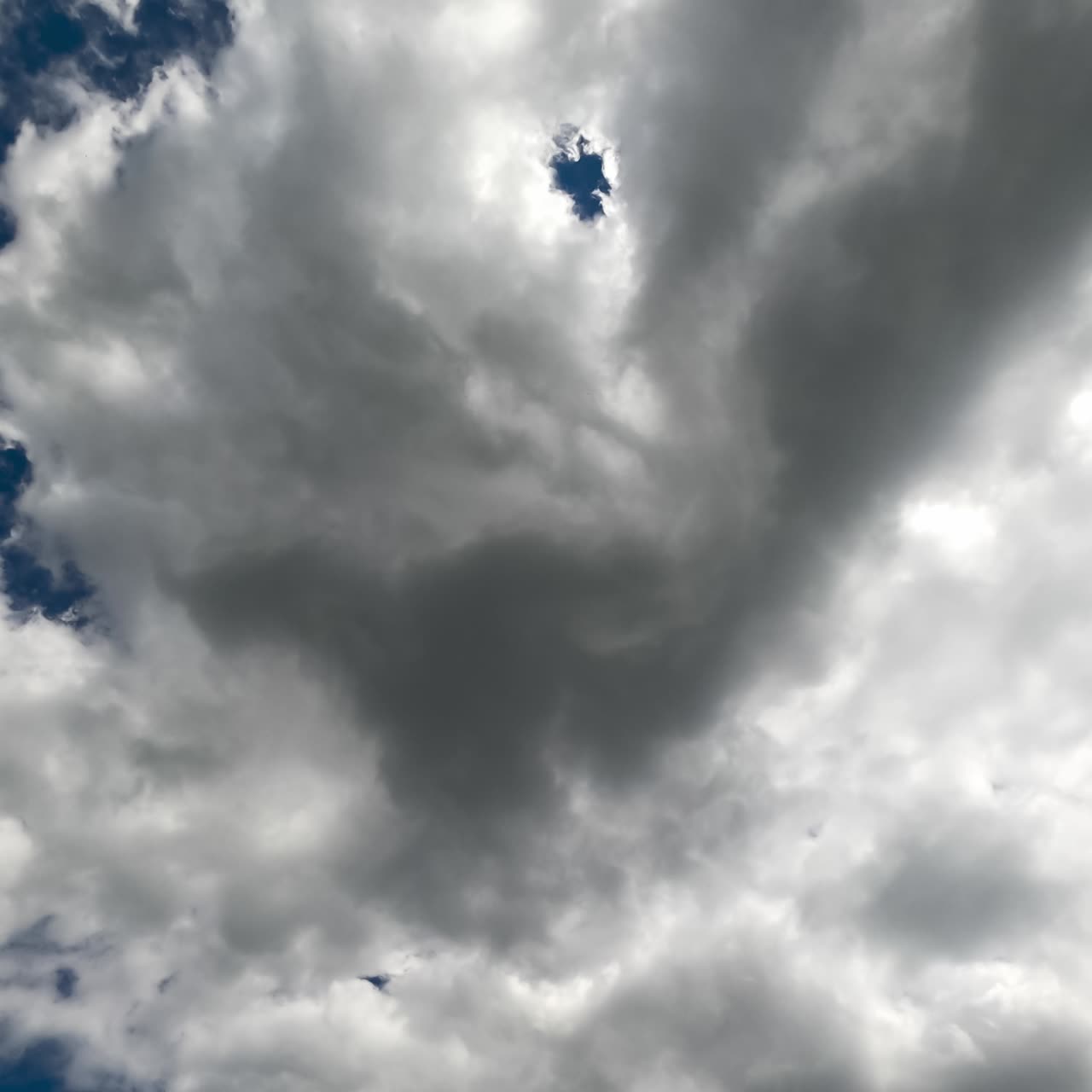 Grey clouds covering the blue sky totally. Bright sun breaking through the cloudscape. Timelapse