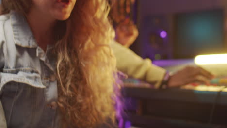 woman playing synthesizer and singing in recording studio