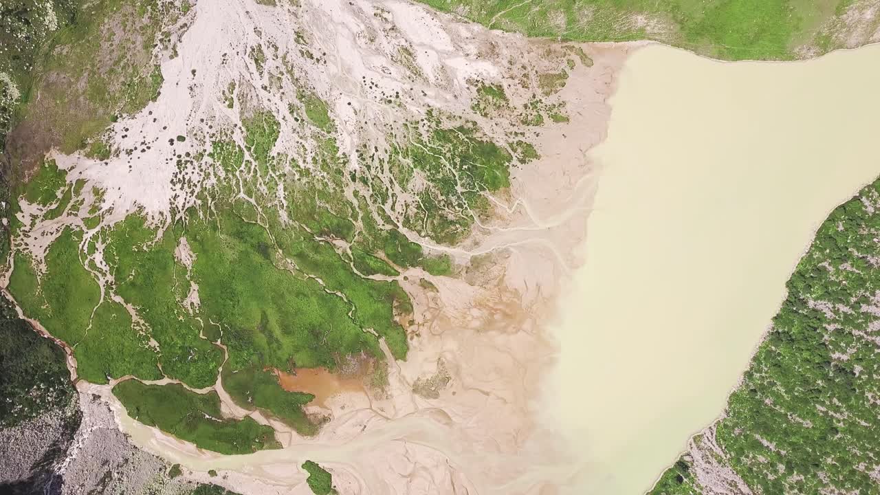 침식 된 땅 과 초록색 식물 이 있는 산 호수 의 공중 사진