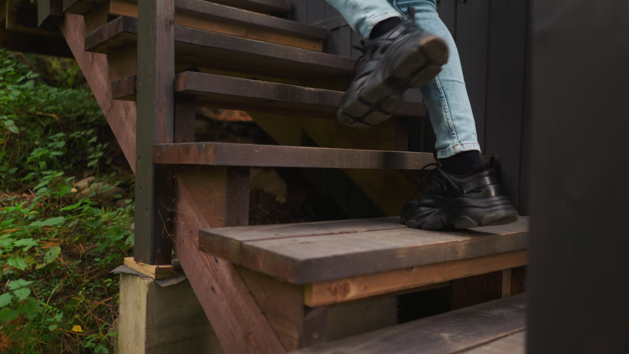 una mujer deportiva llega a casa subiendo las escaleras. una mujer joven prefiere caminar por la mañana en el aire fresco en el bosque en vacaciones de glamping. una mujer casi llega a la cabaña