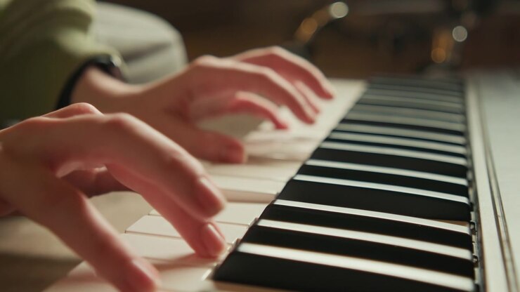 Tight closeup of hands actively playing piano keys, fingers curved and pressing alternating black and white keys while others hover for quick transitions; visible motion blur and varied finger