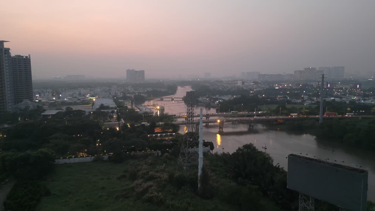 disparo de avión no tripulado volando hacia arriba revelando el horizonte de la ciudad de ho chi minh sobre los puentes de rach dia y el río rach dia visto desde nha be al atardecer con un gran cartel visto en primer plano