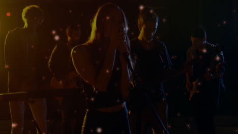 band performing on dimly lit music stage, with floating sparkles and microphone animations