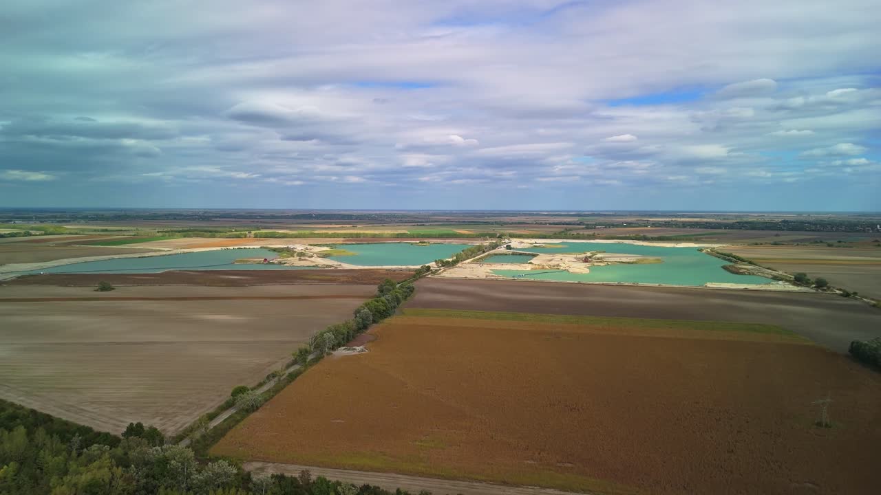 Szalkszentmárton gravel pit and mining lakes from a drone perspective, surrounded by agricultural fields on a cloudy day in Hungary
