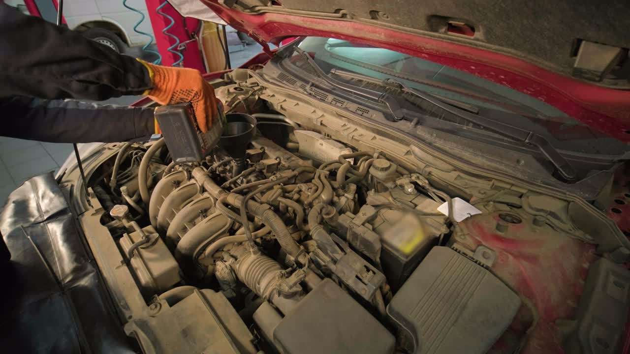 el mecánico de automóviles está cambiando el aceite del motor en un motor en la estación de automóviles.