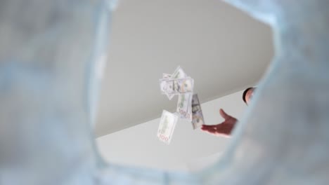 person throwing money into a trash or waste bin