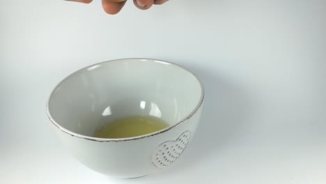 male hands cracking an egg into a white ceramic bowl, still, isolated, slomo