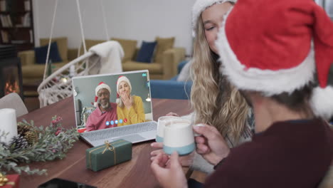 dos parejas felices y diversas teniendo una llamada de video de laptop de navidad, en cámara lenta