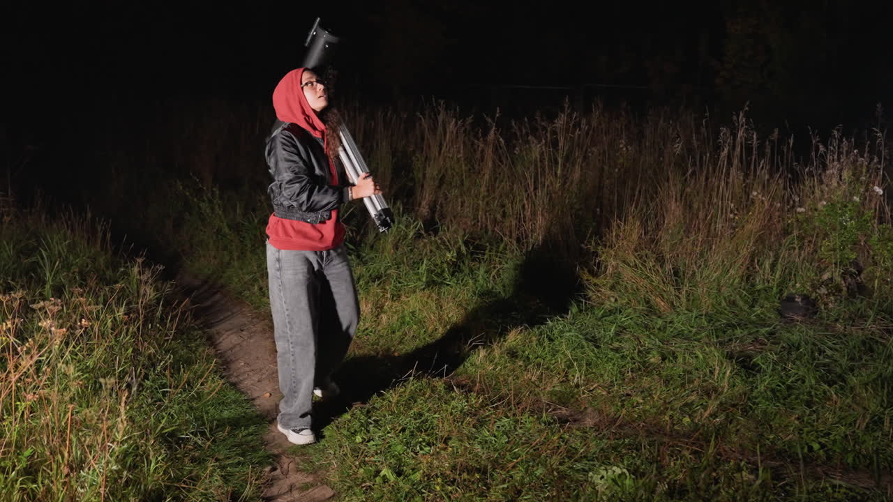 Natstjerneobservatør justerer tungt teleskop, amatørastronom med hætte sætter stativ og okular op, justerer montering og kalibrerer optik, scanner stjerneklar himmel over eng, rolige bevidste bevægelser