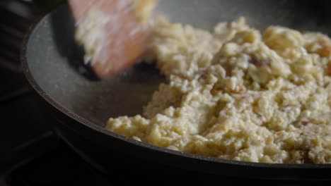 retire la cubierta de la tapa de la sartén caliente y luego revuelva la avena y el queso con una cuchara de madera.