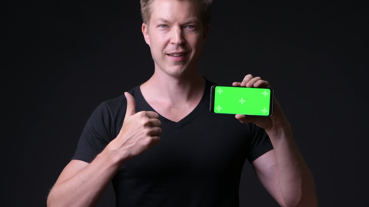 hombre sosteniendo un teléfono móvil con pantalla verde de clave de croma