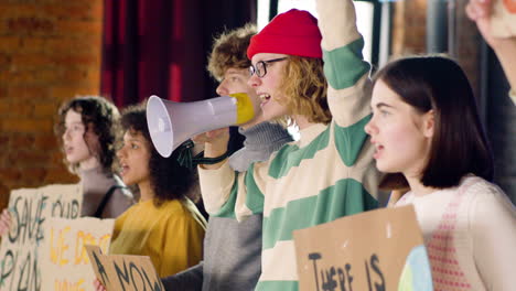 side view of young environmental activists with placards and megaphone protesting against climate change inaction