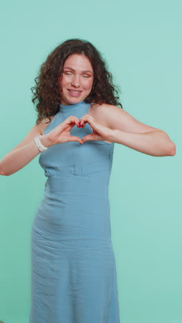 una hermosa mujer sonriente hace un gesto de corazón demuestra un signo de amor expresa buenos sentimientos y simpatía