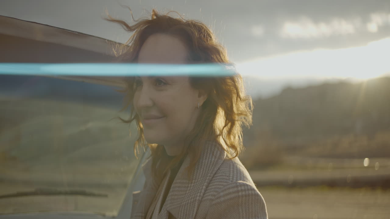 mujer por un coche de época al atardecer