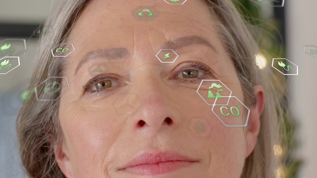 Senior woman following green hex icons showing energy data, smiling, lifting hand and tucking hair