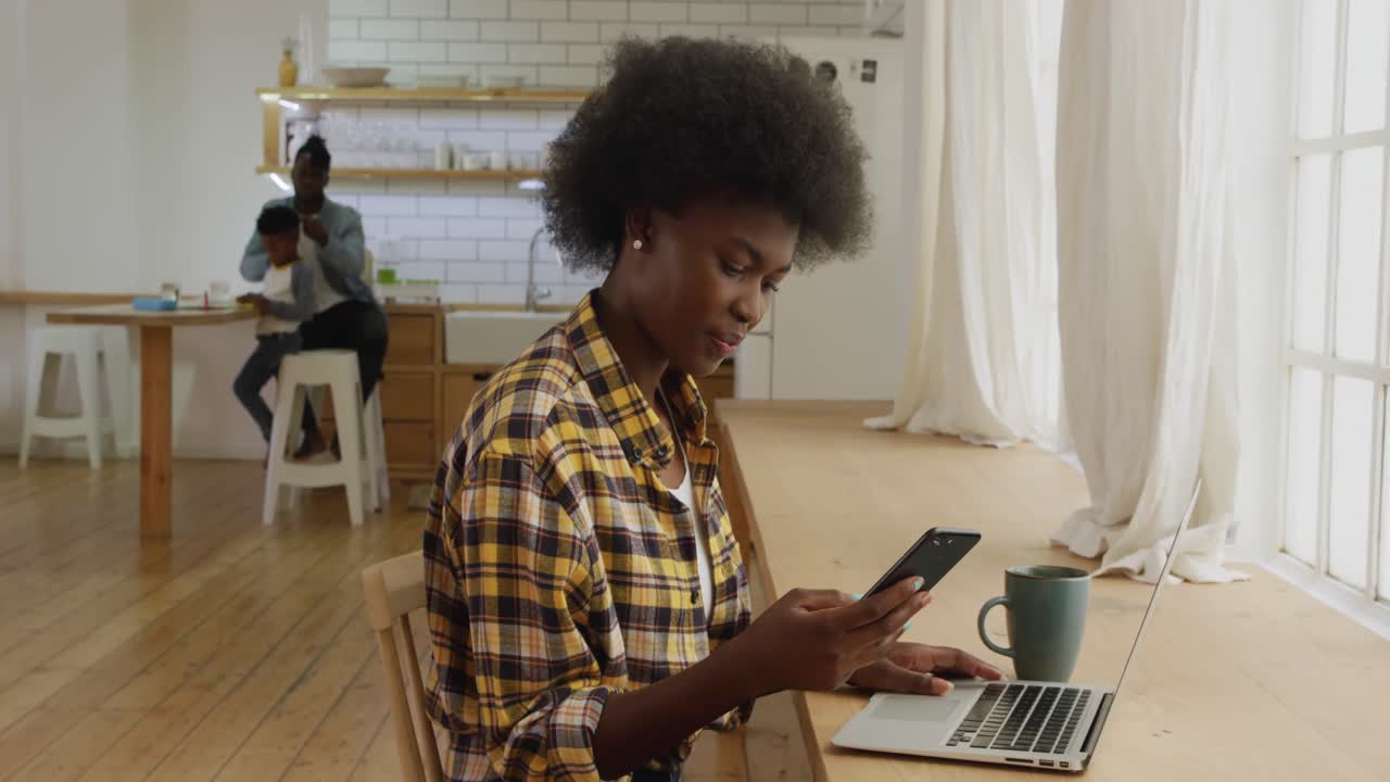 Woman using smartphone and laptop at home