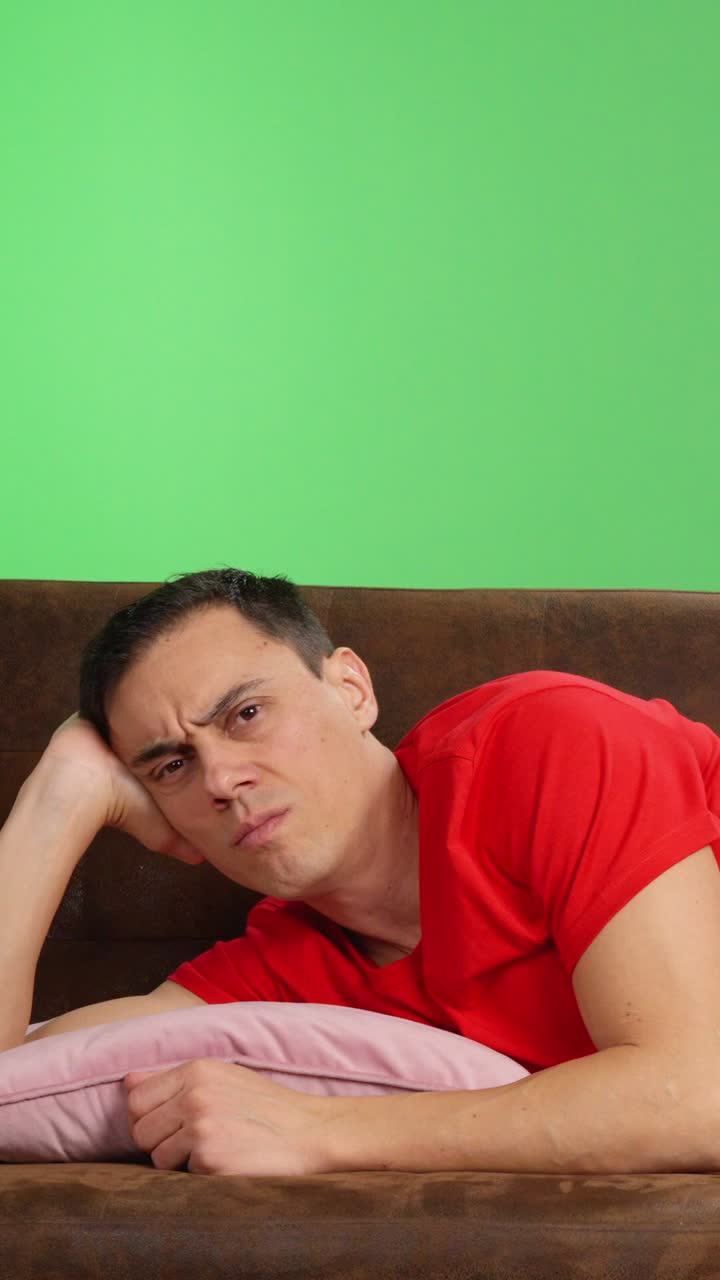 Depressed man lying on couch with remote control