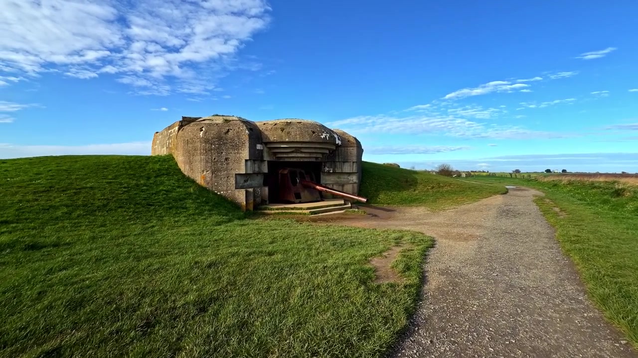 Betonbunker på en græsklædt kystmark ved det historiske batteri Longues-sur-Mer i Frankrig.