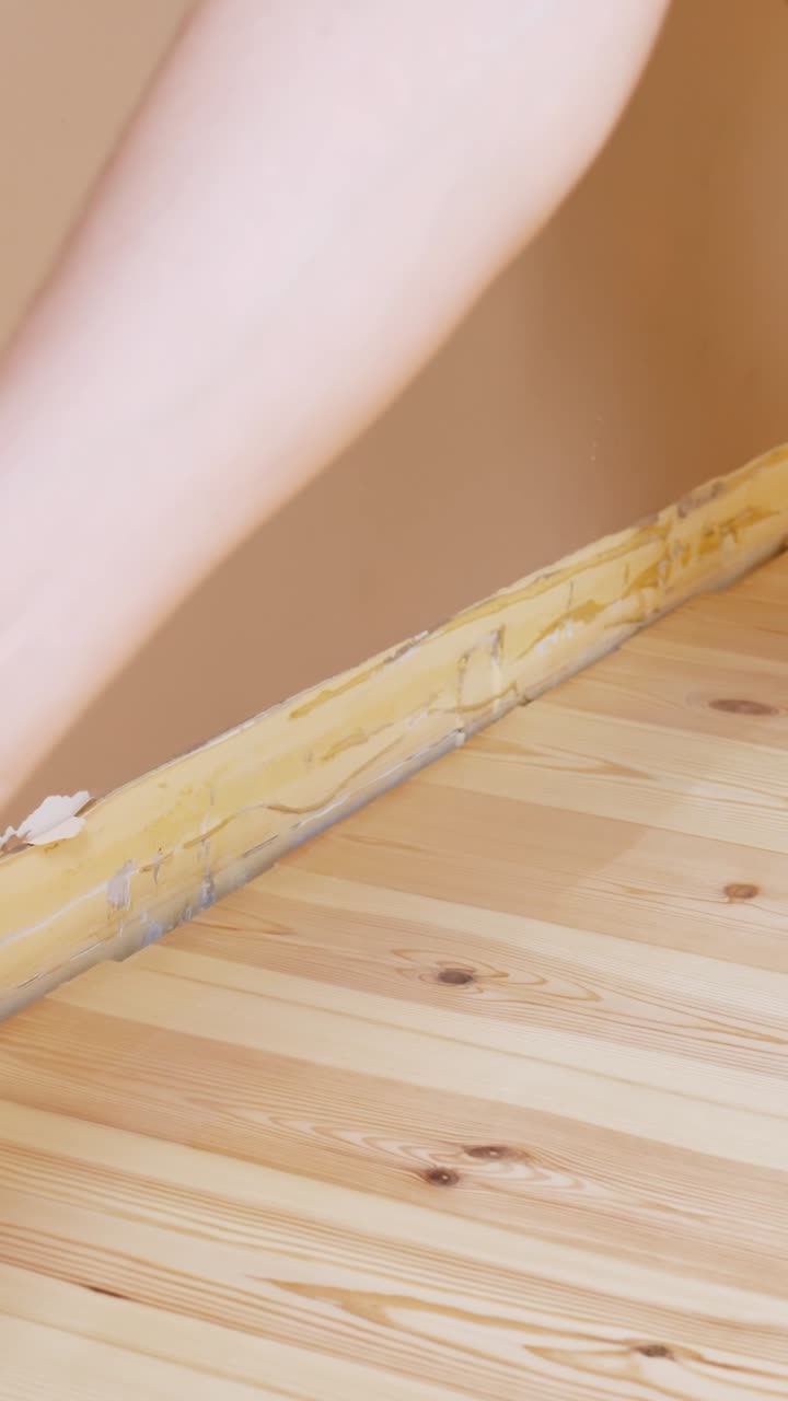 Close-up of vertical varnishing being applied to a hardwood floor, highlighting texture and technique