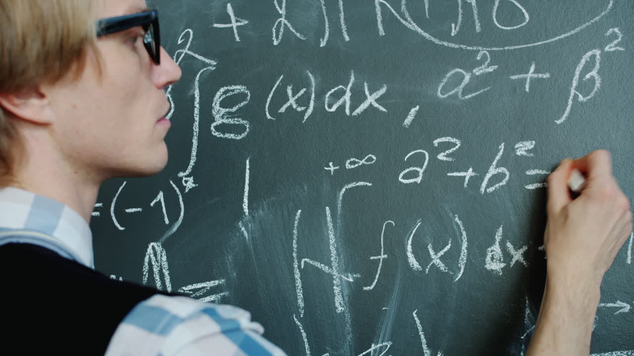Student solving math problems on a blackboard
