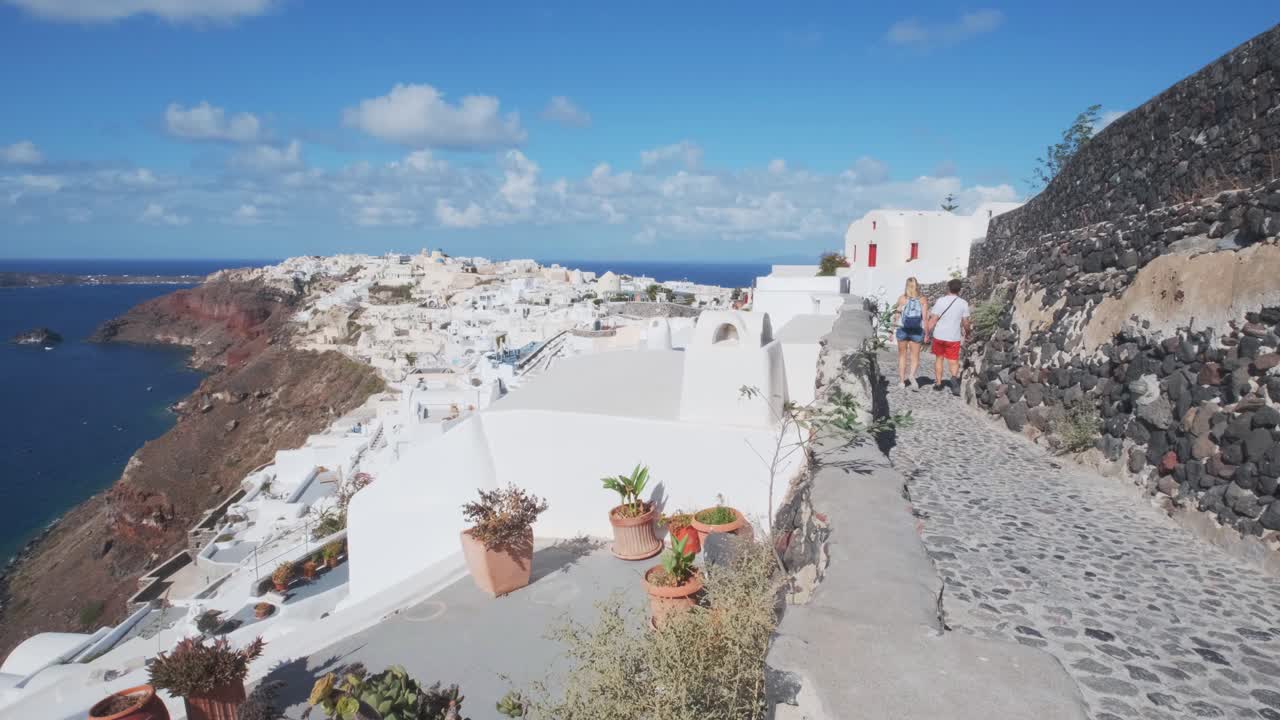 pareja caminando por las calles del pueblo de oia, grecia
