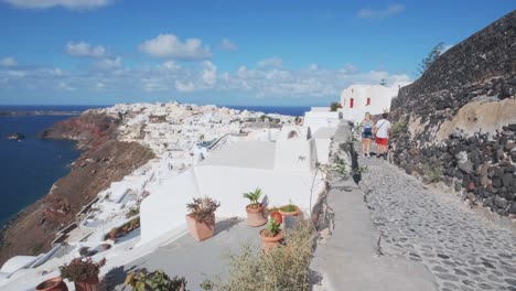 Couple-walking-in-the-streets-of-Oia-village,-Greece