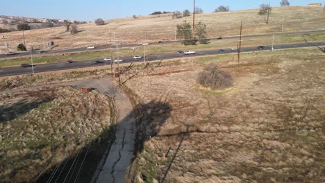 Real-time-drone-footage-close-to-Clarksville,-California,-USA-on-a-bright-sunny-day,-showing-a-a-large-4-lane-highway-and-busy-passing-traffic,-with-hills,-buildings-and-a-road-bridge-in-the-distance