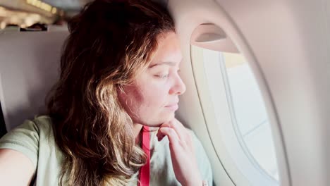 woman looking thoughtfully out of an airplane window