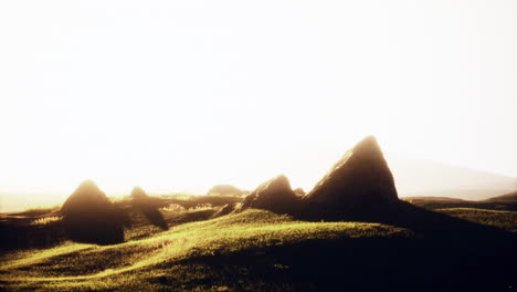 sunset over grassy hill with rocks