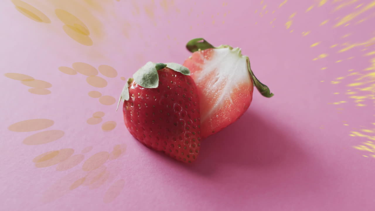 composición de fresas divididas en dos y manchas de luz sobre un fondo rosado