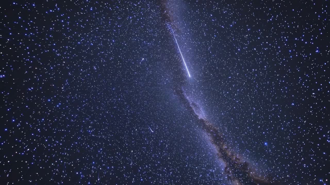 A mesmerizing night sky video with a wide-angle view, capturing a meteor streaking through a dense