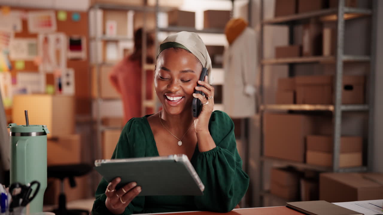 Giovane donna felice che parla al telefono e usa il tablet in ufficio